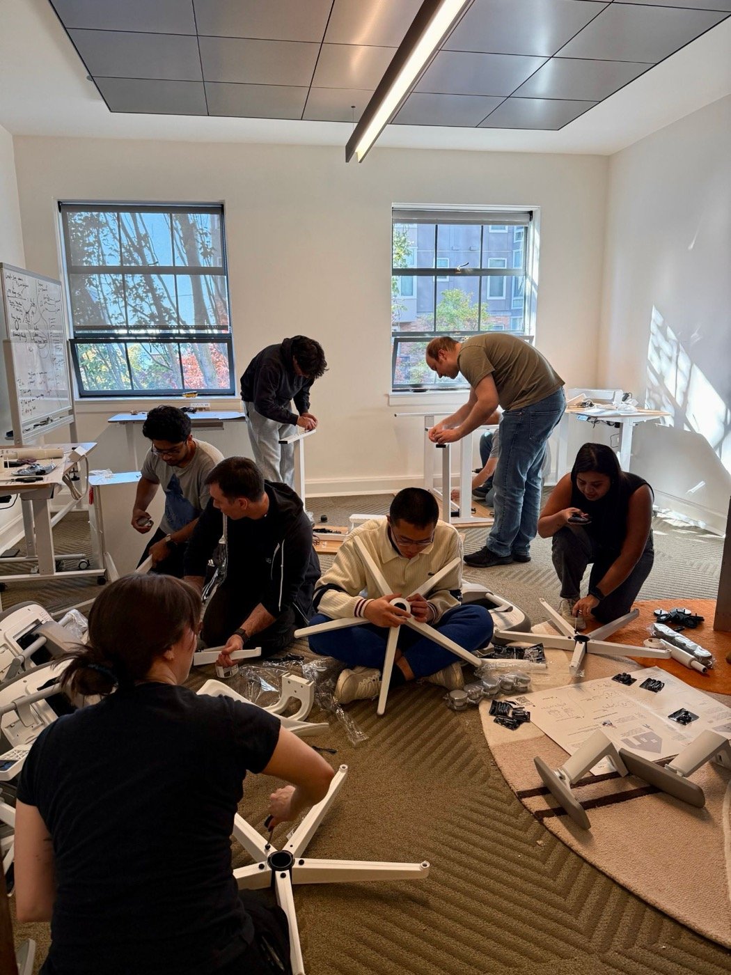 The SageOx team on the office floor, building desks and chairs together