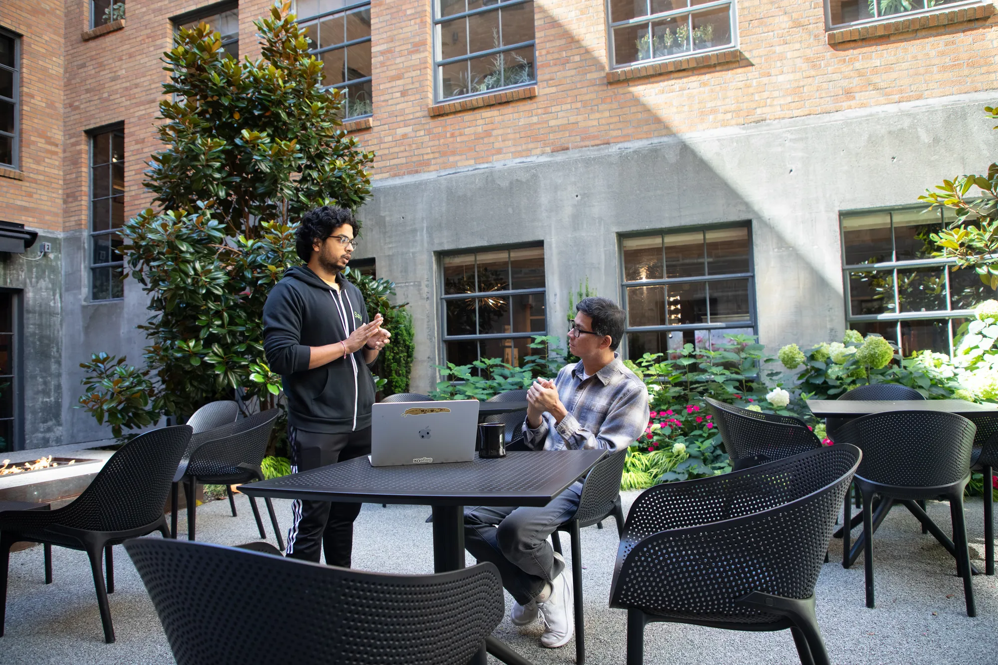 Two SageOx coworkers talking at a table in a courtyard